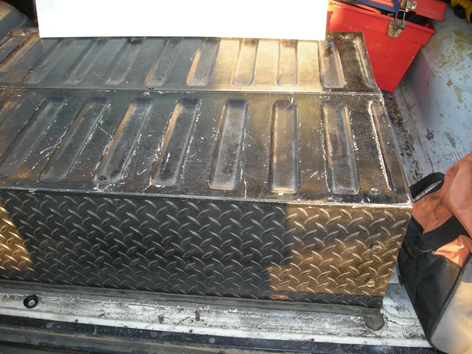 Diamond plate toolbox with ribbed lid, inside a truck bed