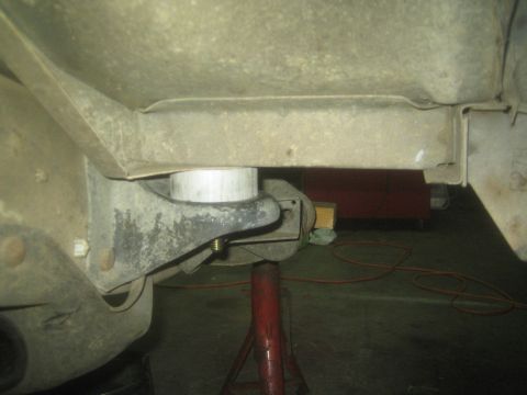 1990 Ford Bronco - Underbody close-up of a truck body mount and bushing resting on a red jack stand.