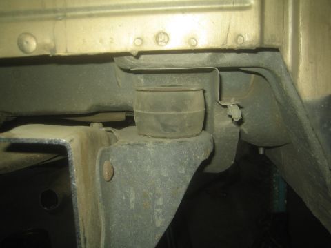 1990 Ford Bronco - Underbody close-up of a truck cab mount, rubber bushing and bracket, with stamped numbers on the sheet metal.