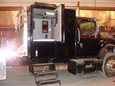 1992 Ford Bronco - This custom truck conversion features a living area with a bed and air conditioning unit inside the rear compartment.