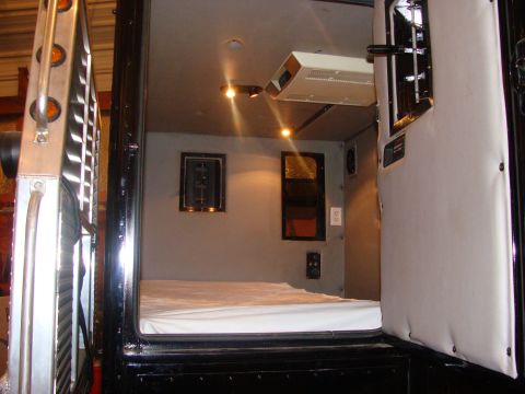 1992 Ford Bronco - The interior of a sleeper cab features a bed, air conditioning unit, and windows.