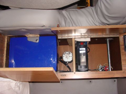 1992 Ford Bronco - Storage compartment inside a vehicle contains various electronic components and a blue storage box.
