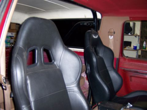1991 Ford Bronco - Interior view of a vehicle with aftermarket racing seats and red trim.