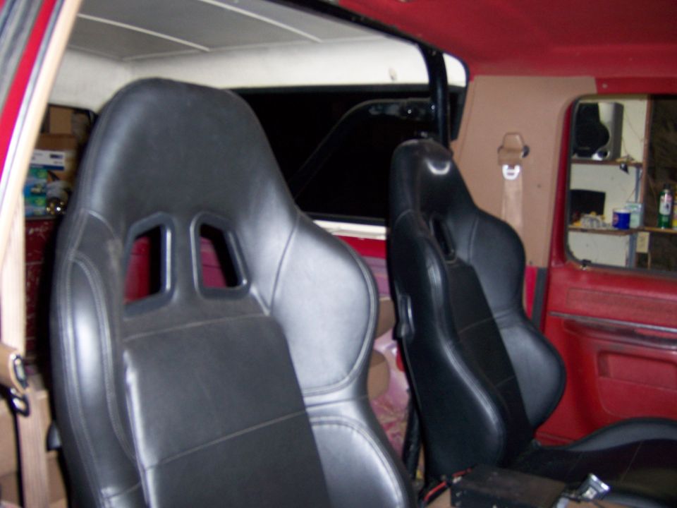 Black racing seats with red interior and tan headliner. Visible roll bar and door panel
