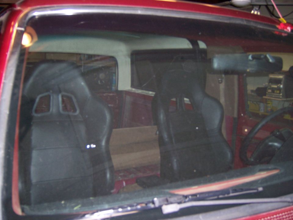 Interior of red vehicle with black racing seats and wooden panels in the back