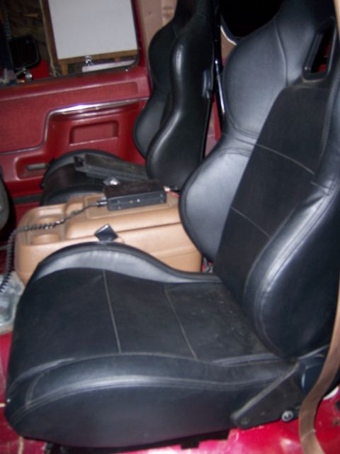 1991 Ford Bronco - Close-up of two black aftermarket bucket seats inside a vehicle, with a tan center console and some electronic equipment.