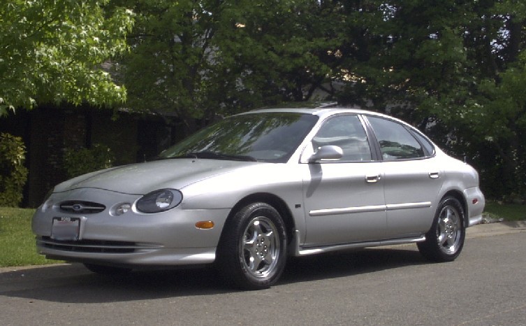 Silver Ford Taurus sedan, three-quarter front view at a curb