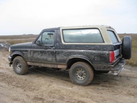 1994 Ford Bronco - 1994 Ford Bronco covered in mud on a dirt track.
