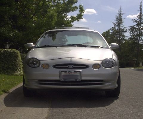 1998 Ford Taurus - A silver 1998 Ford Taurus is shown from the front, parked on a residential street.
