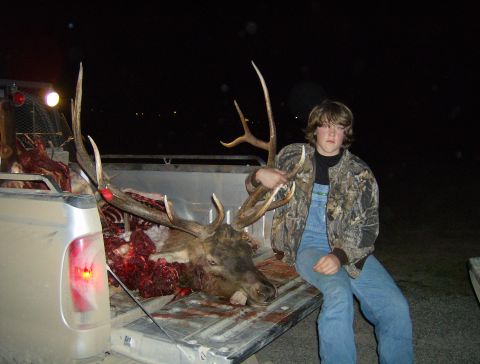 1990 Ford Bronco - A hunter poses with a large elk carcass loaded into the bed of a pickup truck at night.