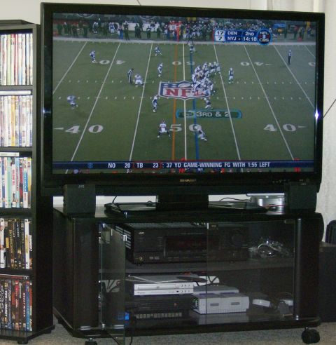 1990 Ford Bronco - A television displays a football game, with a bookshelf full of DVDs to the left.
