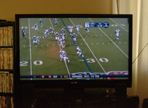 1990 Ford Bronco - A television displays a football game in progress, showing team scores and player statistics at the bottom of the screen.