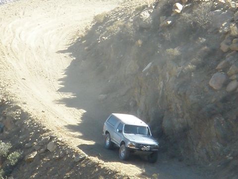 2008 Ford Bronco - A silver SUV navigates a dusty, winding dirt road, likely during an off-road event.