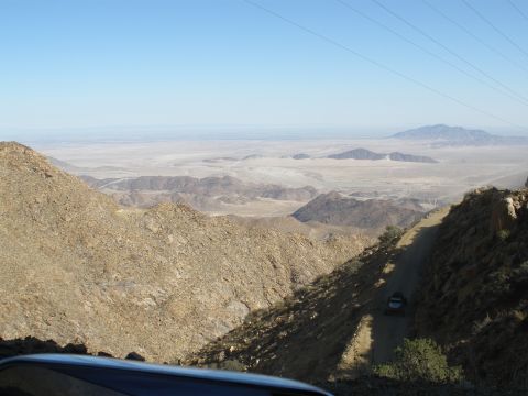 2008 Ford Bronco - View from a mountain road overlooking a vast desert valley with a distant vehicle.
