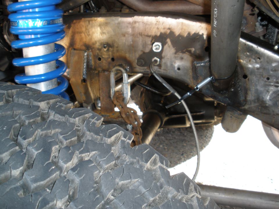 Off-road tire and blue coilover shock assembly on a heavily modified vehicle frame