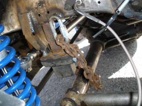 2008 Ford Bronco - Close-up of a modified vehicle suspension system a blue coilover shock and a rusty chain securing a component.