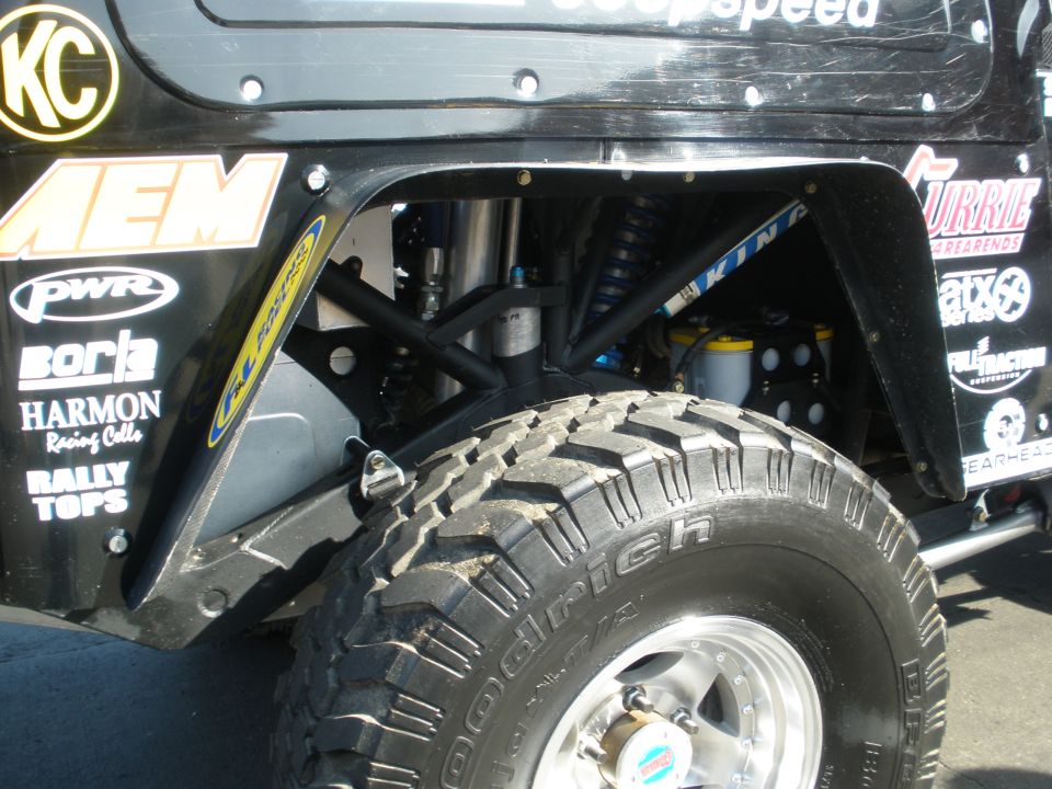 Off-road vehicle's rear wheel well with BFGoodrich tire, visible suspension components, and various sponsor decals