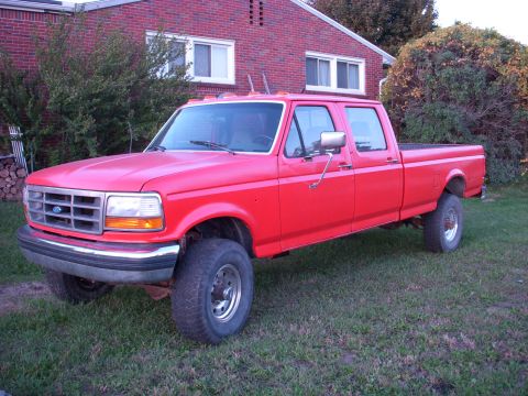 1992 Ford F-350 - This red 1992 Ford F-350 crew cab pickup truck is parked on a grassy lawn in front of a brick house.