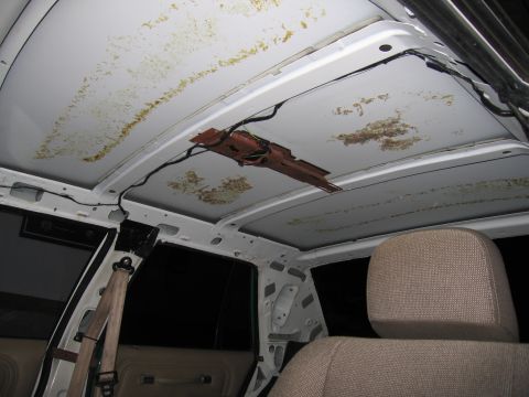 1991 Ford LTD Crown Victoria - Interior view of a vehicle roof showing yellow adhesive residue and bare metal after headliner removal.