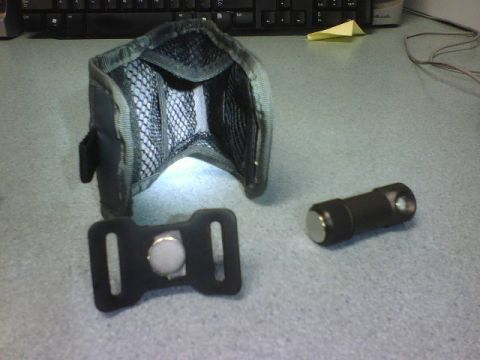 1984 Ford Bronco - A black flashlight and its accompanying holster are displayed on a desk, with a magnetic clip visible.