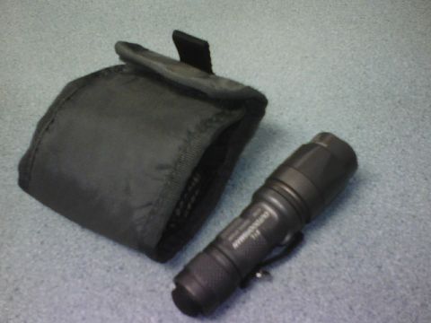 1984 Ford Bronco - Tactical flashlight and its protective case are shown on a textured surface.