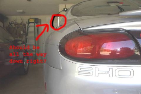1998 Ford Taurus - A red arrow and text overlay question the position of the car's antenna, with another vehicle partially visible in the background.