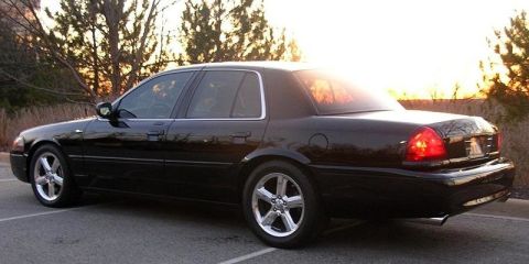2003 Mercury Marauder - A black 2003 Mercury Marauder is captured in a rear three-quarter view against a backdrop of trees and a setting sun.