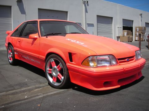 1998 Ford Crown Victoria - This modified Ford Mustang features a bright orange paint job and custom five-spoke wheels.