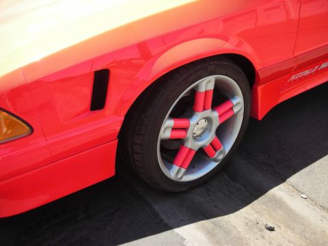 1998 Ford Crown Victoria - A close-up of a red car's fender and a custom wheel with red accents.