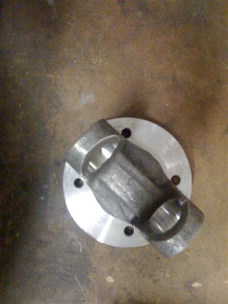 1987 Suzuki Samurai - A close-up view of a U-joint component, likely for a drivetrain, resting on a workshop surface.