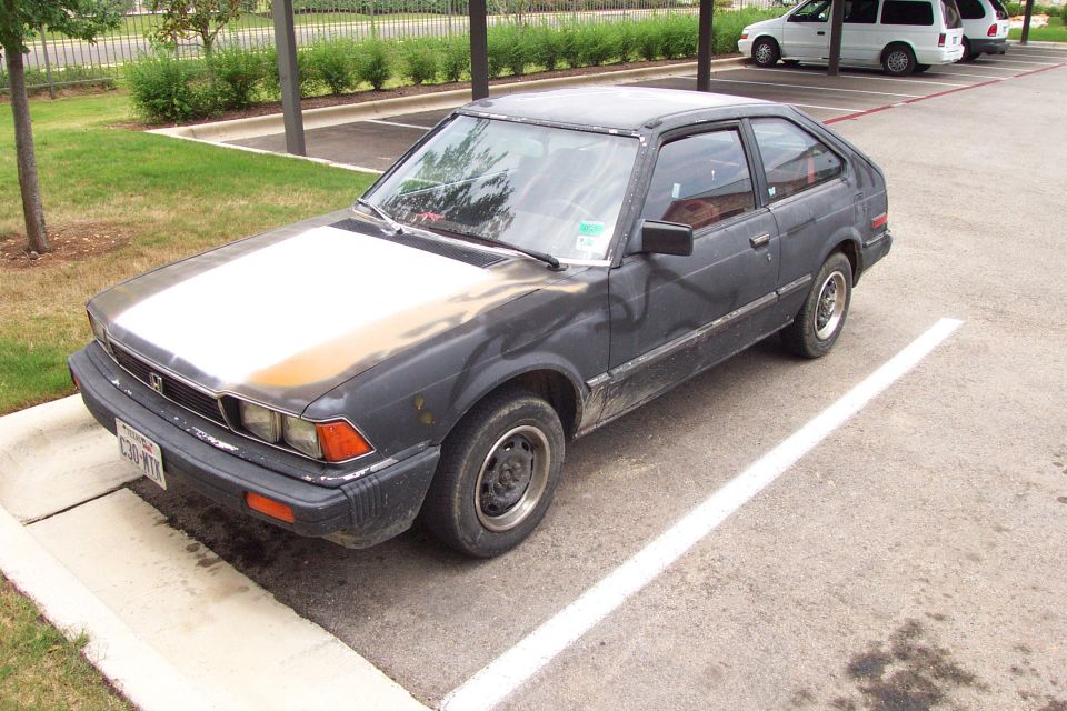 Faded dark gray Honda Accord hatchback parked at 3/4 front angle in a lot