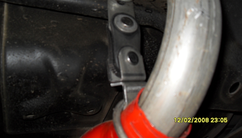 Close-up of a vehicle's exhaust pipe held by a metal bracket. Date stamp reads 12/02/2008