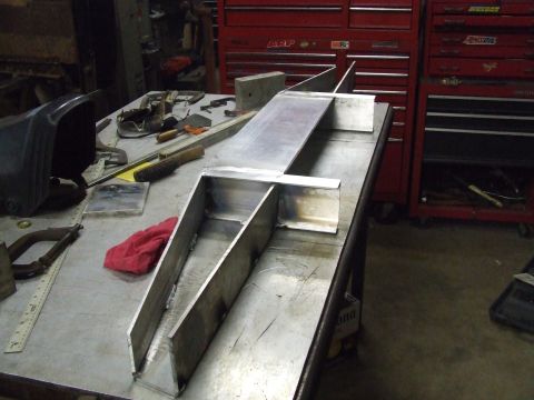1967 Ford Bronco - Custom metal part being fabricated on a workbench, surrounded by tools and shop equipment.