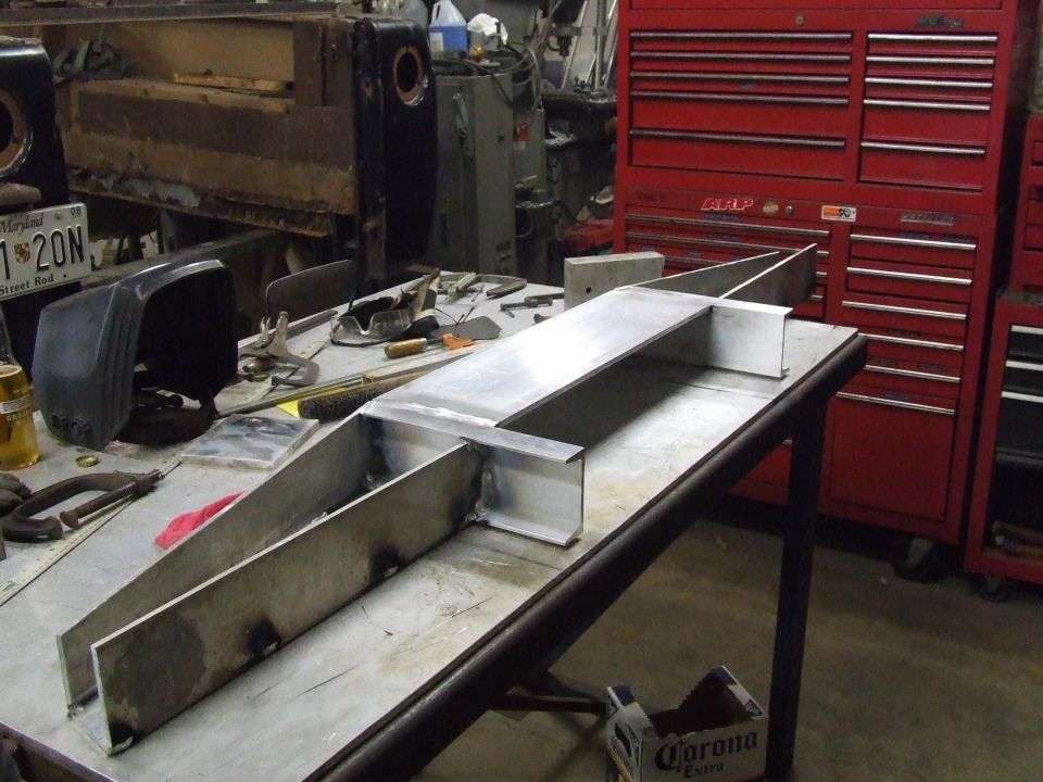 Welded aluminum structure on a workbench with tools and a red toolbox in the background
