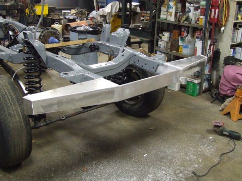 1967 Ford Bronco - A vehicle's frame and suspension system are shown in a workshop setting with a custom bumper installed.