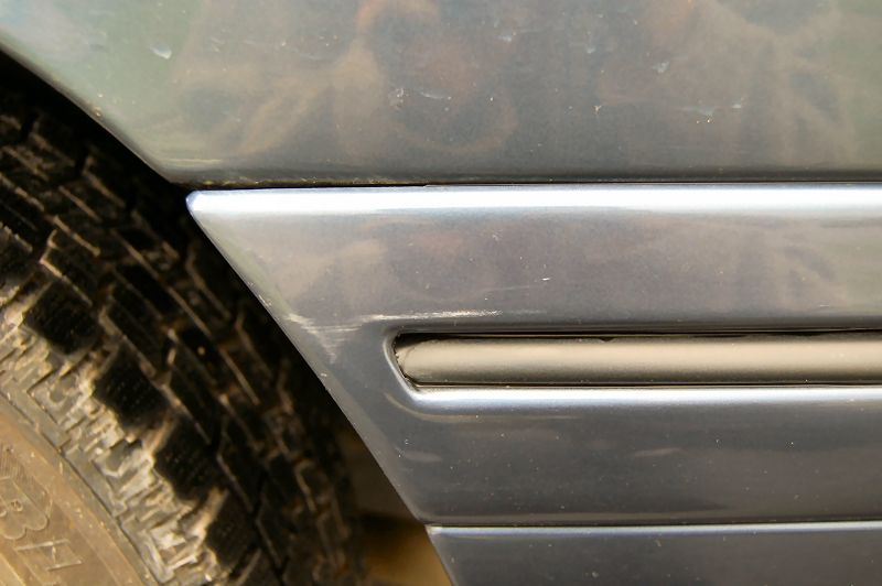 close-up of a car's rear fender trim and tire