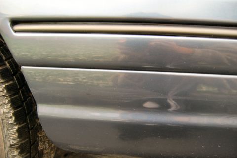 1985 Mercury Grand Marquis - Close-up of a car's side panel reveals a tire and a chrome trim piece, with a watermark at the bottom.
