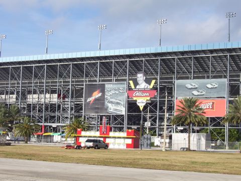 1979 Chevrolet Camaro - Daytona International Speedway grandstands display various advertisements and a portrait of a race car driver.