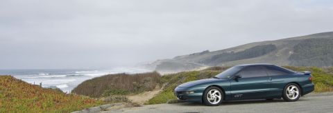 1996 Ford Probe - A 1996 Ford Probe sits on the side of a road overlooking the ocean on a cloudy day.