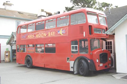 1996 Ford Probe - A red double-decker bus, possibly a former public transport vehicle, is parked next to a building.