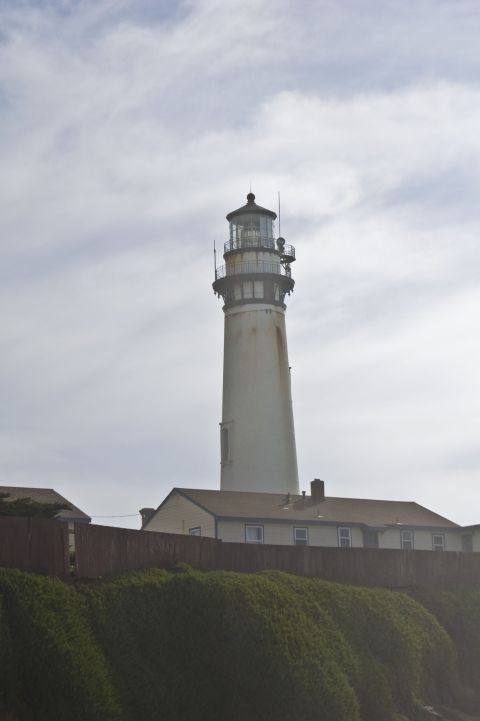 1996 Ford Probe - A lighthouse stands tall above buildings and a fence, with a cloudy sky overhead.