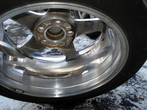 1998 Ford Taurus - A close-up view of a chrome wheel and tire, with visible dirt and water on the surface.