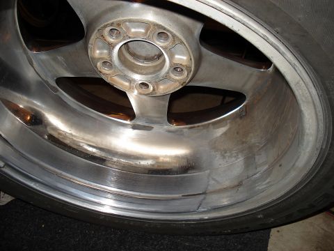 1998 Ford Taurus - Close-up view of a chrome alloy wheel, showing its five-spoke design and lug nut mounting points.