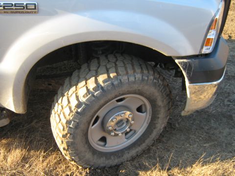 1990 Ford Bronco - Close-up of a silver Ford F-250 Super Duty truck's front wheel and fender assembly.