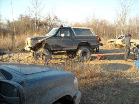 1990 Ford Bronco - A heavily modified 1990 Ford Bronco with a snorkel and off-road tires is seen in a field with another truck.