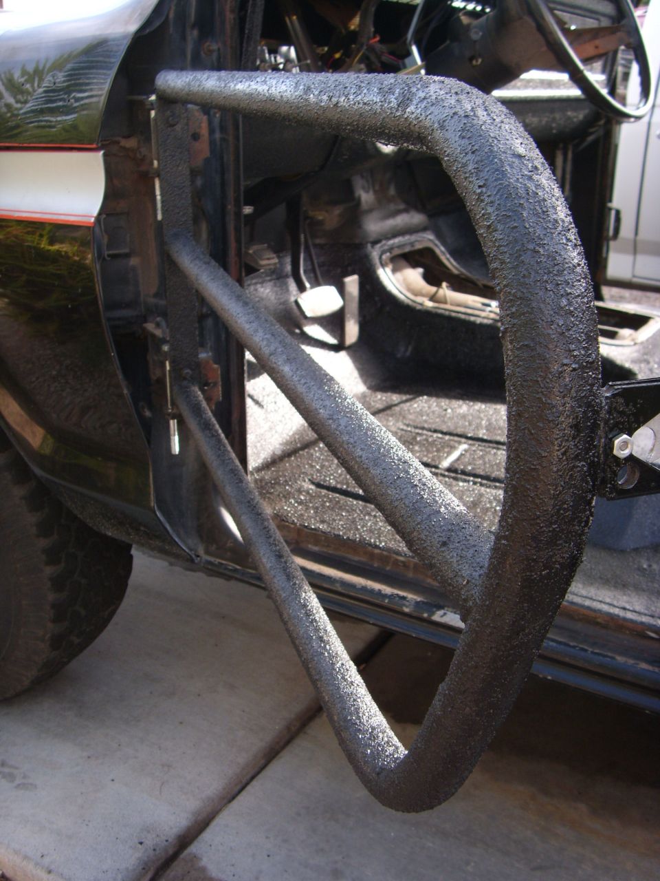 Close-up of aftermarket tube doors mounted inside a vehicle, showing pedals and floor