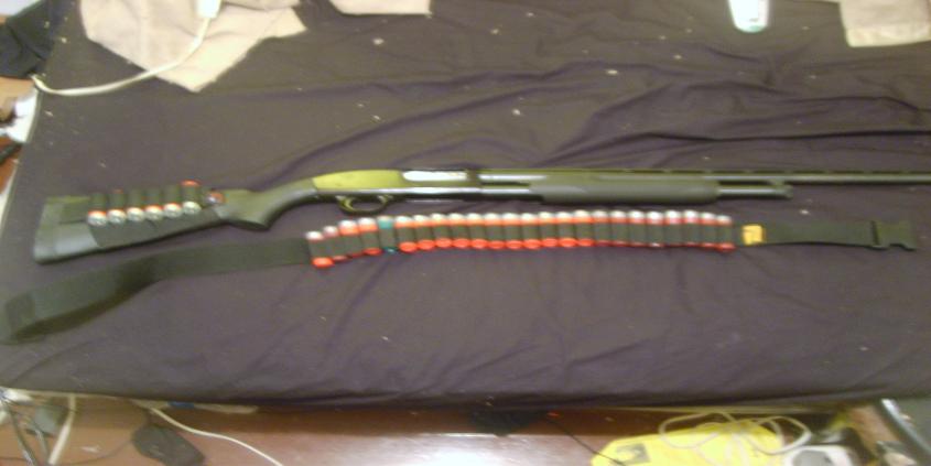 Shotgun with a black sling and a bandolier holding red-tipped shells