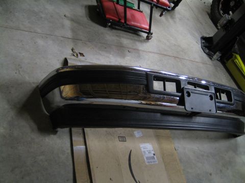 1996 Ford Bronco - A detached front bumper is shown resting on cardboard in a garage or workshop setting.