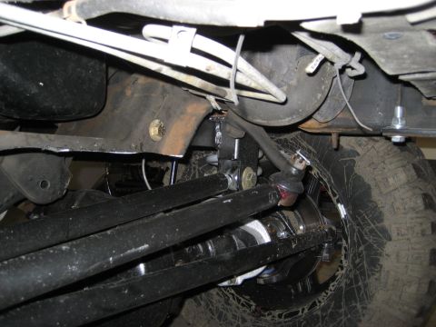 1996 Ford Bronco - A close-up view of a vehicle's undercarriage reveals suspension parts and a tire.