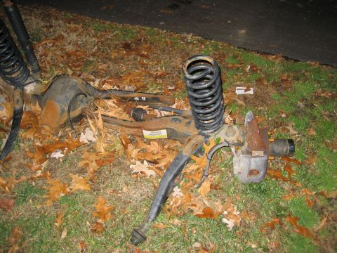1996 Ford Bronco - Discarded vehicle suspension components, including the rear axle and coil springs, are shown on the ground.